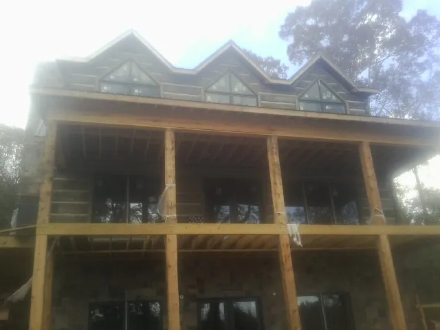 Dormers and porch framing on a large log home under construction — Roof Coating work by our crew in Sale Creek