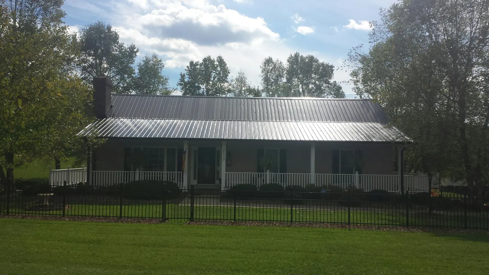 Gray metal roof on a brick ranch with a full width front porch — Gutter Guard Installation work by our crew in Sale Creek
