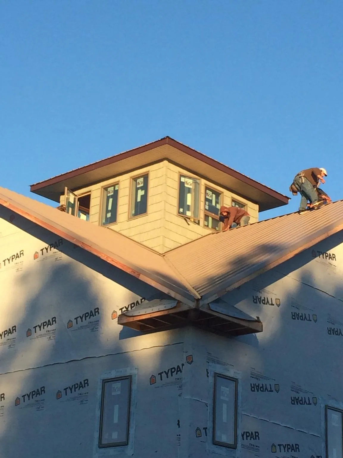 Roofers working around a rooftop cupola on a new metal roof at sunset — Roof Waterproofing in Sale Creek by Roofing Brothers